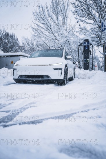 A modern electric car is parked in a snowy area next to a charging station, Tesla Model Y electric car, ENBW charging station, Waldachtal, Freudenstadt district, Germany