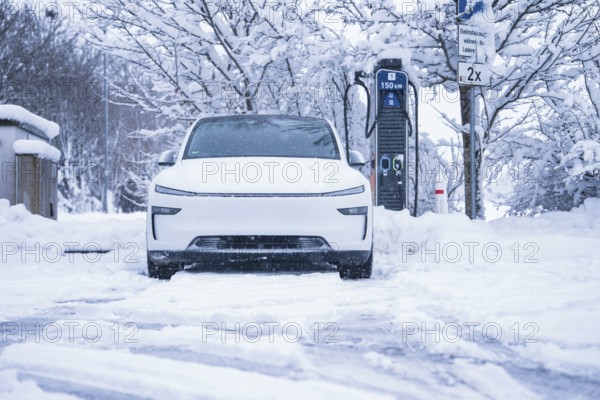 An electric car is parked in a snowy winter landscape next to a charging station, Tesla Model Y electric car, ENBW charging station, Waldachtal, Freudenstadt district, Germany