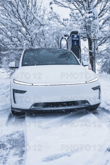 White electric car charging at a charging station in a snowy winter landscape, Tesla Model Y electric car, ENBW charging station, Waldachtal, Freudenstadt district, Germany