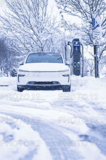 An electric car is parked on a snowy road next to a charging station, Tesla Model Y electric car, ENBW charging station, Waldachtal, Freudenstadt district, Germany