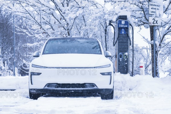 An electric car parked in the snow, close-up of the charging station in the background, Tesla Model Y electric car, ENBW charging station, Waldachtal, Freudenstadt district, Germany