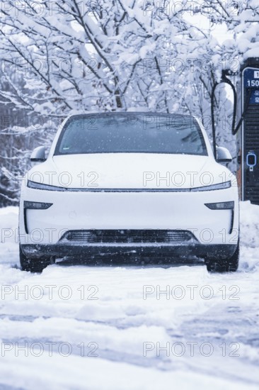 A futuristic white electric car stands in the snow in front of a charging station, Tesla Model Y electric car, ENBW charging station, Waldachtal, Freudenstadt district, Germany