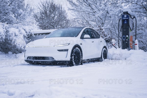 Electric car in a snowy area stands next to a charging station, Tesla Model Y electric car, ENBW charging station, Waldachtal, Freudenstadt district, Germany