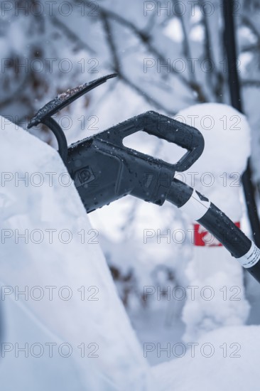 Close-up of a charging cable connected to a car in a snowy environment, Tesla Model Y electric car, ENBW charging station, Waldachtal, Freudenstadt district, Germany