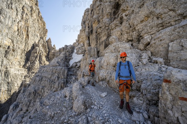 Two mountaineers on the Via Ferrata Bocciere Centrale via ferrata, spectacular mountain landscape with steep rock faces, Brenta Mountains, Parco Naturale Brenta-Adamello, Trentino, Italy
