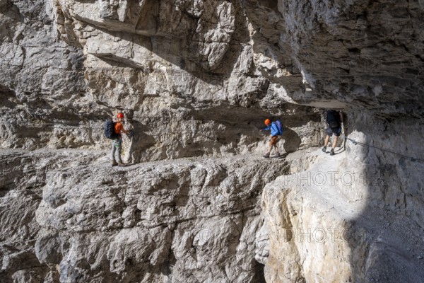 Mountaineers on an exposed rock band in the secured via ferrata Bocciere Centrale, Brenta Mountains, Parco Naturale Brenta-Adamello, Trentino, Italy