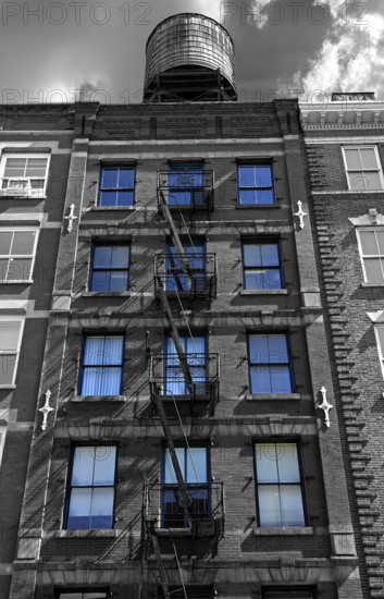Residential building with fire escapes and wooden water tank on the roof, black and white, Downtown NY, New York City, USA