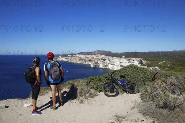 Cyclists look at the ville haute or upper town or medieval old town of Bonifacio, Corse-du-Sud department, Corsica, France