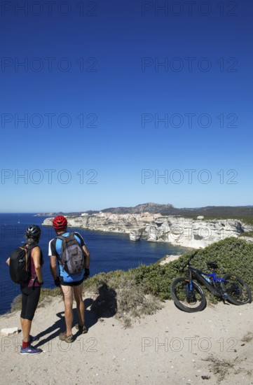Cyclists look at the ville haute or upper town or medieval old town of Bonifacio, Corse-du-Sud department, Corsica, France