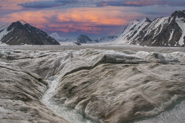 Glaciers with meltwater at sunset against an impressive, snow-covered mountain backdrop in Altai Tavan Bogd National Park, Mongolia
