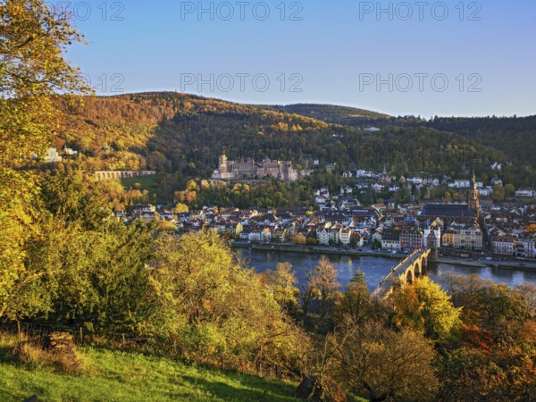 Heidelberg, view from Philosophenweg across the Neckar to the Old Bridge, Old Town and Heidelberg Castle in an autumn atmosphere with colorful autumn leaves and blue sky, Baden-Württemberg, Germany