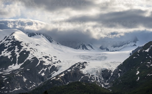Mountain peak with Worthington Glacier glacier, dramatic cloudy sky, picturesque landscape on Richardson Highway, Chugach Mountains, Alaska, USA
