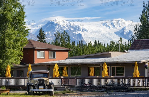 Vintage car and historic building in front of mountain landscape with Kennicott Glacier, McCarthy, Wrangell St. Elias National Park, Alaska, USA
