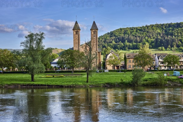Moselle river, St. Salvator church, double tower, general architecture, houses, riverbank, hilly landscape, hills, forest, trees, meadow, abstract reflections on the water surface, blue sky, cumulus clouds, dramatic image processing, country road L98, Valwig, Cochem-Zell district, Rhineland-Palatinate, Germany