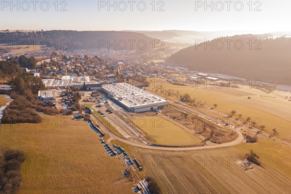 Factory next to a village in a hilly landscape on a winter morning, Glatten, Freudenstadt district, Germany