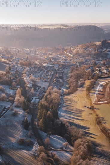 Aerial view of a snowy village in a hilly landscape at sunrise with long shadow plays, Glatten, Freudenstadt district, Germany