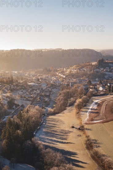 Aerial view of a snowy village at sunrise with snow-covered trees and hills in the background, Glatten, Freudenstadt district, Germany