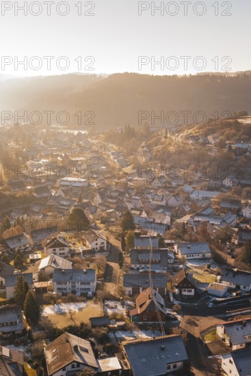View of a village in winter at sunrise with snow-covered roofs and a golden atmosphere, Glatten, Freudenstadt district, Germany