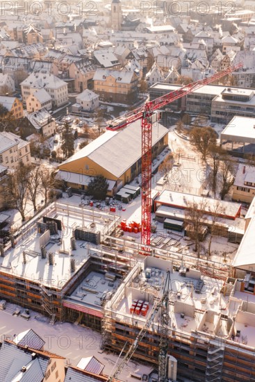 Snowy town with a construction site and a distinctive red crane, Zellerschule building, Nagold, Black Forest, Germany
