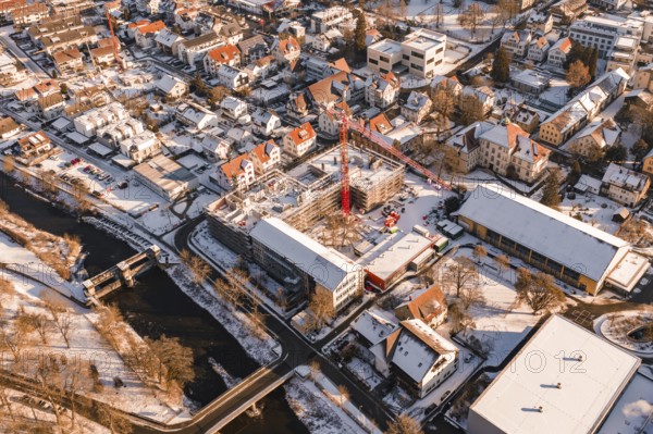 Snowy town with a red construction crane on a construction site and a river, Neubau Zellerschule, Nagold, Black Forest, Germany