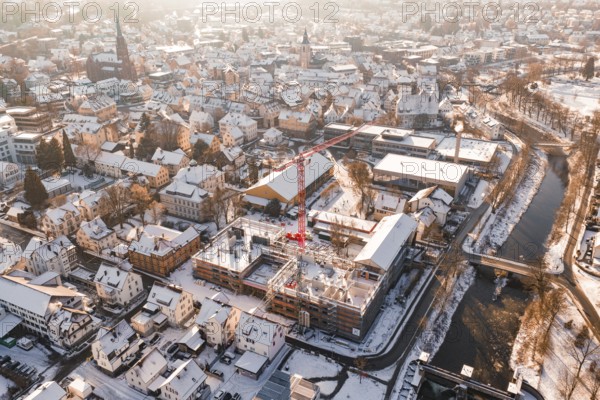 City in winter with an active construction site and visible church roof in the background, Zellerschule building, Nagold, Black Forest, Germany