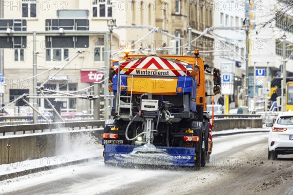Winter in Stuttgart. There is a closed blanket of snow in the city center. Snowplow in winter service sprinkles road salt. Stuttgart, Baden-Württemberg, Germany