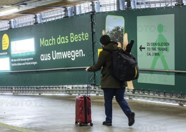 Construction work at Stuttgart Central Station as part of Stuttgart 21. Travelers have to accept long detours to get to the platform. Advertising banners on the makeshift footbridge refer to the detour through access to the tracks ridiculed as a long-distance hiking trail. Stuttgart, Baden-Württemberg, Germany
