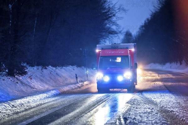 Ambulance during an alarm trip, with flashing lights, in winter, slush, slippery roads, country road near Marienheide, Bergisches Land North Rhine-Westphalia, Germany