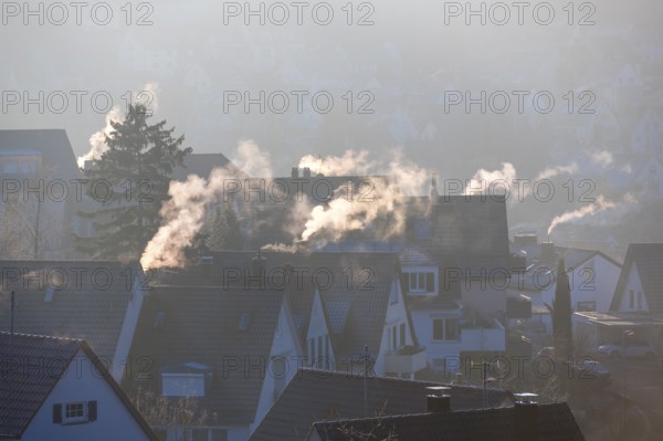 Quiet village view with smoking chimneys in the morning winter light, symbolic image, fireplaces, gas heating, oil heating, fossil fuels, climate change, global warming, chimneys, Baden-Württemberg, Germany