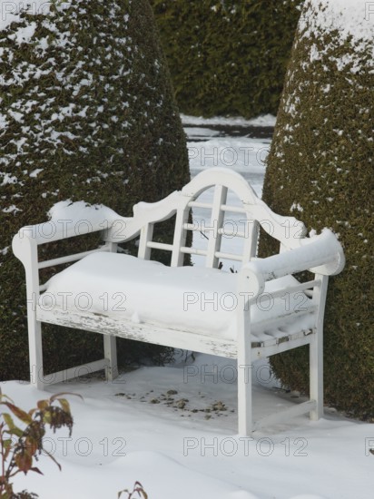 White snow upholstery on the white garden bench, East Frisia, Germany