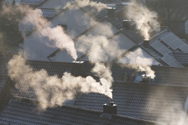 Smoking chimneys over roofs in a winter atmosphere illuminated by sunrays, symbolic image, fireplaces, gas heating, oil heating, fossil fuels, climate change, global warming, chimneys, Baden-Württemberg, Germany