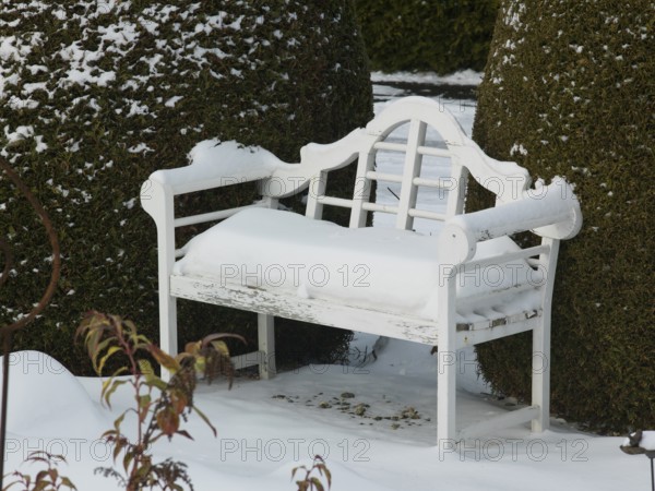 White snow upholstery on the white garden bench, East Frisia, Germany