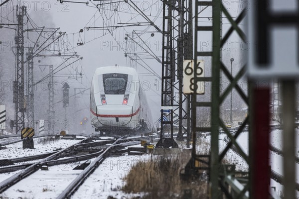 ICE traveling through a winter landscape in snowfall. A train on the line in the Deutsche Bahn Amstetten rail network, Baden-Württemberg, Germany