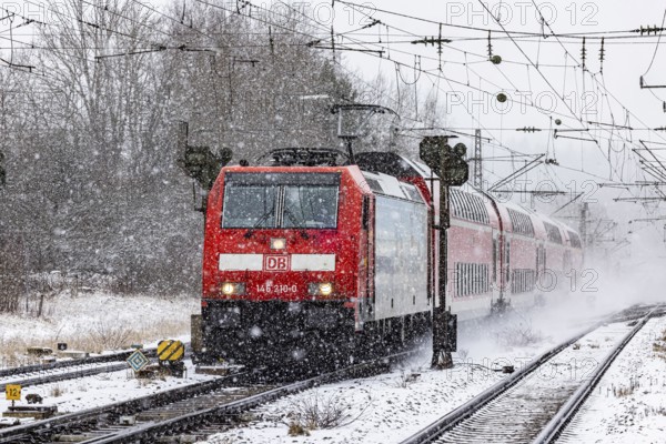RegionalExpress RE on the road through a winter landscape in snowfall. A train on the line in the Deutsche Bahn AG rail network. Amstetten, Baden-Württemberg, Germany