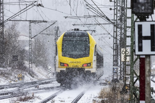Regional train from Arverio on its way through a winter landscape in snowfall. The railcar train is painted by the Baden-Württemberg mobility brand bwegt. A train on the line in the Deutsche Bahn AG rail network. Amstetten, Baden-Württemberg, Germany