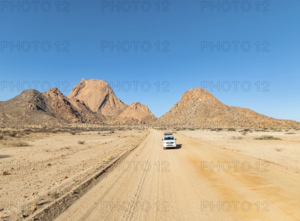 Car on sandy road, mountains in the desert, Spitzkoppe summit, Namib desert, Namibia