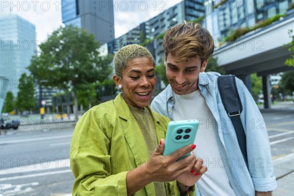 Business colleagues standing outdoors in a city, happily sharing and viewing content together on a smartphone, representing connection, communication, and collaboration