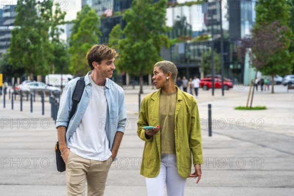 Diverse business colleagues walking outdoors through a modern city park, having an engaging conversation while discussing ideas and collaborating on their project