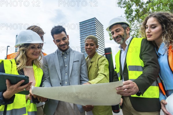 Group of multi ethnic architects, engineers, and entrepreneurs wearing hard hats and safety vests, gathering outdoors to review and discuss building plans at a construction site in a modern city