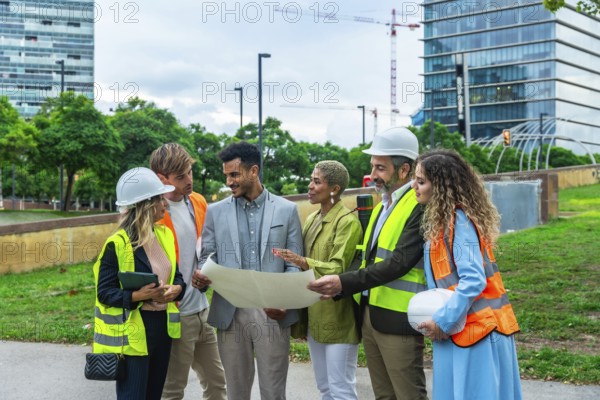 Group of multi ethnic architects, engineers, and executives reviewing blueprints and discussing plans for a new city development, symbolizing teamwork, innovation, and professional collaboration