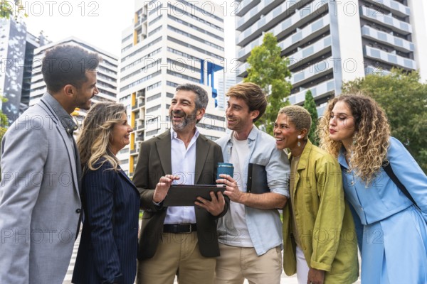 Diverse business professionals working together laughing outdoors, analyzing a digital tablet, fostering teamwork and shared success in a modern city setting