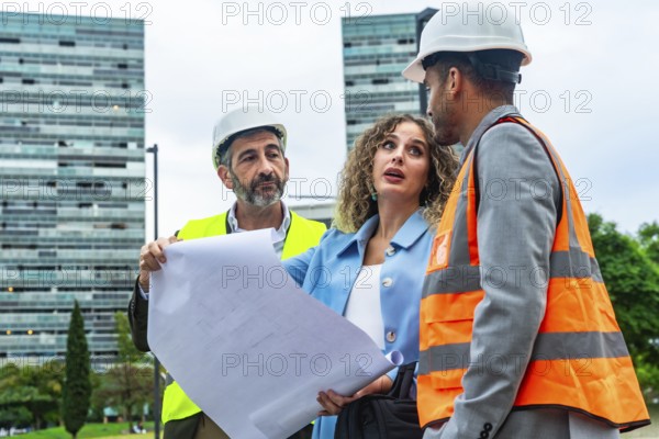 Three construction professionals, including an architect and an engineer, reviewing building blueprints and discussing an urban development project on site with modern buildings in the background