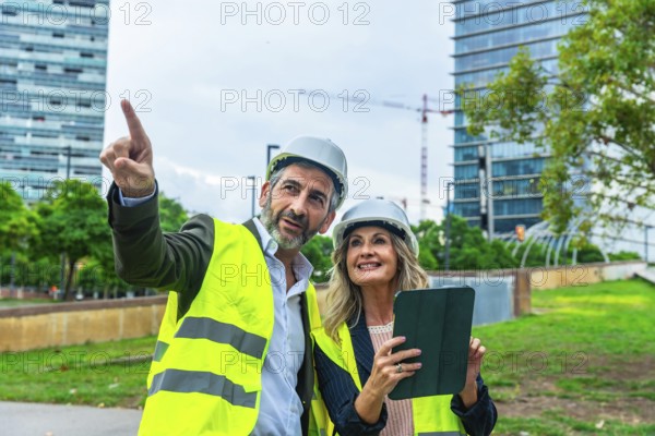 Architects and engineers review development plans on a tablet while pointing toward a construction site, collaborating on urban planning, smart city design and future growth strategies