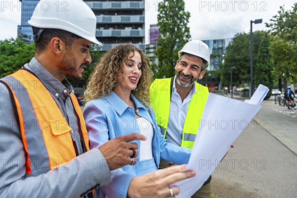 Diverse group of construction professionals discussing architecture plans and collaborating on a new building project, standing on a street in an urban environment
