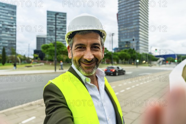 Smiling bearded construction professional in hard hat and safety vest stands on an urban site, confident architectengineer portrait suggesting planning, leadership and modern development