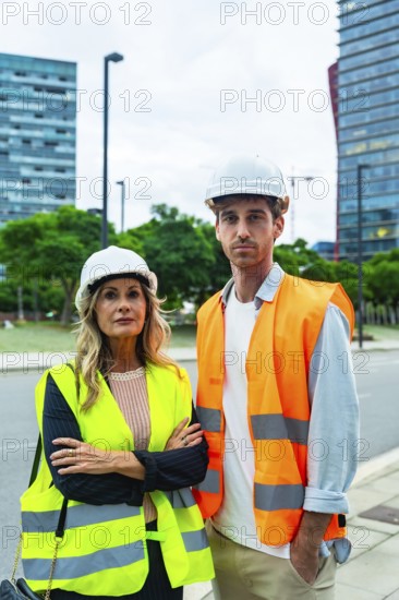Construction professionals wearing hard hats and reflective vests, standing outdoors, collaborating on an urban building project with modern architecture in the background
