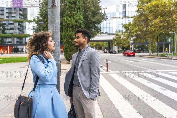 Diverse business professionals having a discussion while standing on an urban street near a crosswalk, reflecting concepts of communication and collaboration in a city environment