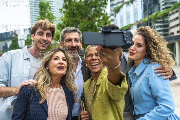 Diverse group of smiling business professionals and executives taking a happy selfie with a camera outdoors in the city, enjoying a moment of teamwork and success together
