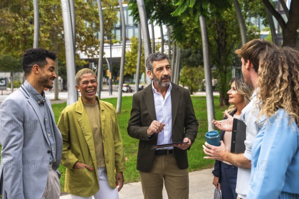 Diverse group of business professionals meeting, exchanging ideas, and smiling outdoors in a modern city park, fostering teamwork and collaborative discussions