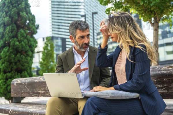 Two business professionals sit on a city park bench, collaborating over a laptopcasual outdoor meeting capturing teamwork, discussion, strategy and mobile corporate work